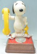 A vintage 1970's novelty Snoopy telephone having a wooden base with a number dial to the front