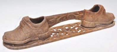 An early 20th Century cast iron bootscrape having a pierced scrolled design base with shoes to