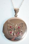 A stamped 925 silver pendant necklace having a round locket with butterfly decoration set with red