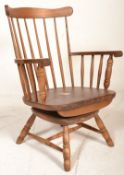 An early 20th century spindle back swivel Windsor arm chair having shaped arm supports and raised on