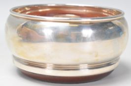 A good silver hallmarked wine coaster having a round bulbous body raised on a wooden base.