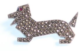 A stamped sterling silver brooch in the form of a Daschund of stylised angular form, being set