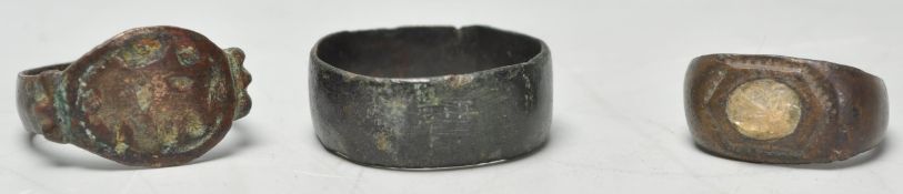 A collection of 3 Roman rings to include a bronze band ring, copper hammered ring with partial