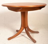 A vintage retro teak wood dining table having a round extending table top raised on four central
