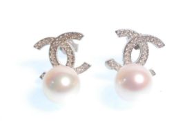 A pair of stamped 925 designer style earrings being set with white accent stones and pearl drops.