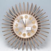 A retro mid 20th century starburst wall clock with circular dial and sunburst surround frame with