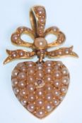 A 19th Century Victorian gold pendant in the form of a heart with a ribbon atop, set with seed