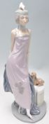 A Lladro figurine depicting a 1920's flapper girl with a feather headdress and puppy. Marked