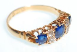 A hallmarked 18ct gold ring set with three round cut sapphires set alternately with four round cut