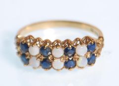 A hallmarked 9ct yellow gold ring set with opals and blue stones set to a decorative scroll mount.