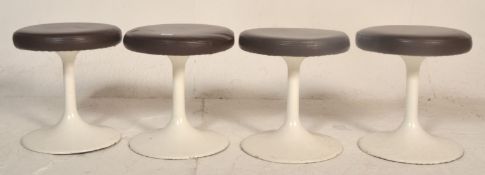 A group of four vintage retro low stools having round leather upholstered seats raised on column