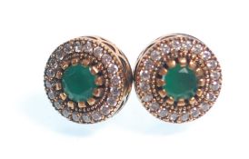 A pair of stamped 925 silver stud earrings of round form being set with round cut green stones and