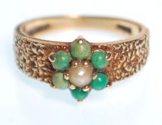 A hallmarked 9ct gold ring having bark effect shoulders with a flower head seat with green stone