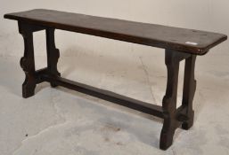 A 19th Century Victorian pine church bench having a plank top raised on two carved and shaped