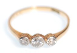 A stamped 18ct gold three stone diamond ring set with three round cut diamonds in a platinum