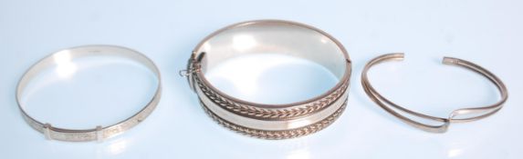 A group of three bangles to include a twist design bangle, a bangle with engraved foliate decoration
