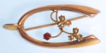 A 19th Century Victorian brooch stamped 9ct gold moulded as a wishbone set with a red faceted cut