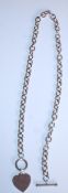A silver necklace having an oval link chain with a toggle clasp and heart pendant. Measures 19