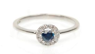 A stamped 18ct white gold ring set with a round cut sapphire and a halo of diamonds. Weight 1.8g.