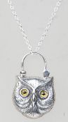 A silver pendant necklace having a shield shaped lock pendant in the form of an owl with glass