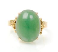 A stamped 14ct gold ring set with a round domed green jade cabochon with decorative floral design