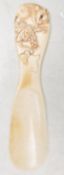 An early 20th Century Japanese ivory shoe horn having a carved handle in the form of a rat on a