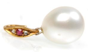 A stunning large cultured pearl pendant on a gold bail set with a single ruby flanked by diamonds.