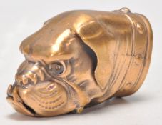 A brass vesta case in the form of a dogs head being set with orange glass eyes, having a match