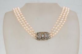 A vintage pearl necklace having three rows of graduating cultured pearls with a silver paste set box