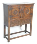 An early 20th Century 1920's carved Ipswich oak cupboard on stand having a twin door cupboard with