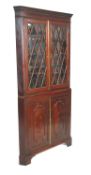 A 19th Century mahogany corner cabinet having a twin door cupboard base with carved panelled