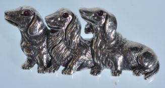 A stamped sterling silver brooch in the form of three Dachshunds set with ruby eyes. Weight 10g.