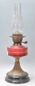 A 19th Century Victorian oil lamp having a round black lacquered plinth base with a cranberry