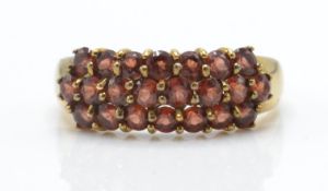 A 9ct gold garnet cluster ring. The ring inset with 22 round cut  orange / red garnet stones on
