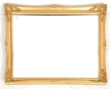 A contemporary antique style gilt wall mirror with shaped cushion frame surrounding bevelled edge