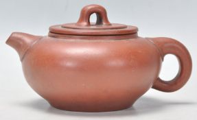 An early 20th Century Chinese Yixing red clay teapot of squat form having a short spout and finial
