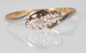 A stamped 18ct gold crossover ring set with three diamond chips set in platinum. Weight 1.7g. Size