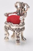 A stamped sterling silver pincushion in the form of a chair having red velvet cushion. Weight 17g.