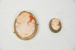 Two antique cameo brooches having oval carved conch shell panels, the larger mounted in yellow metal