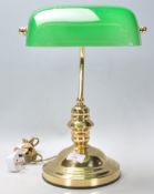 A vintage 20th Century bankers desk lamp having a round stepped base with a green glass rotating