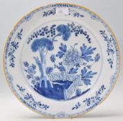 A large 18th Century Delft blue and white Chinese style wall charger plate being hand painted with
