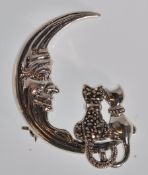 A stamped sterling silver brooch in the form of a crescent moon with two sitting cats set with