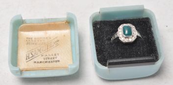 A stamped 9ct gold and silver art deco ring set with a green stone with a halo of white accent