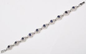 A stamped 925 silver line bracelet set with oval cut sapphires with haloes of round cut CZ's