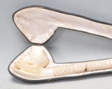 A late 19th Century Victorian long carved Meerschaum mask head pipe having a craved stem and amber