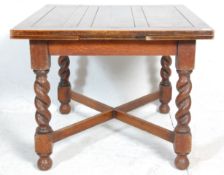 An early 20th Century oak draw leaf dining table having a square top on four barley twist supports
