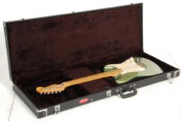 A Fender Stratocaster / strat six string electric guitar having a metallic green body with a white