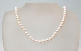 A freshwater pearl necklace of white pearls, having a gold ball clasp. Measures 17 inches. Clasp