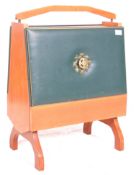 A vintage retro teak wood magazine rack, the fall front upholstered in blue leather with a crest