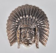 A stamped sterling silver brooch in the form of a Native American wearing a feather headdress,